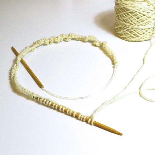White yarn wrapped around a wooden knitting needle to show how to easily cast on using the Long Tail Cast On