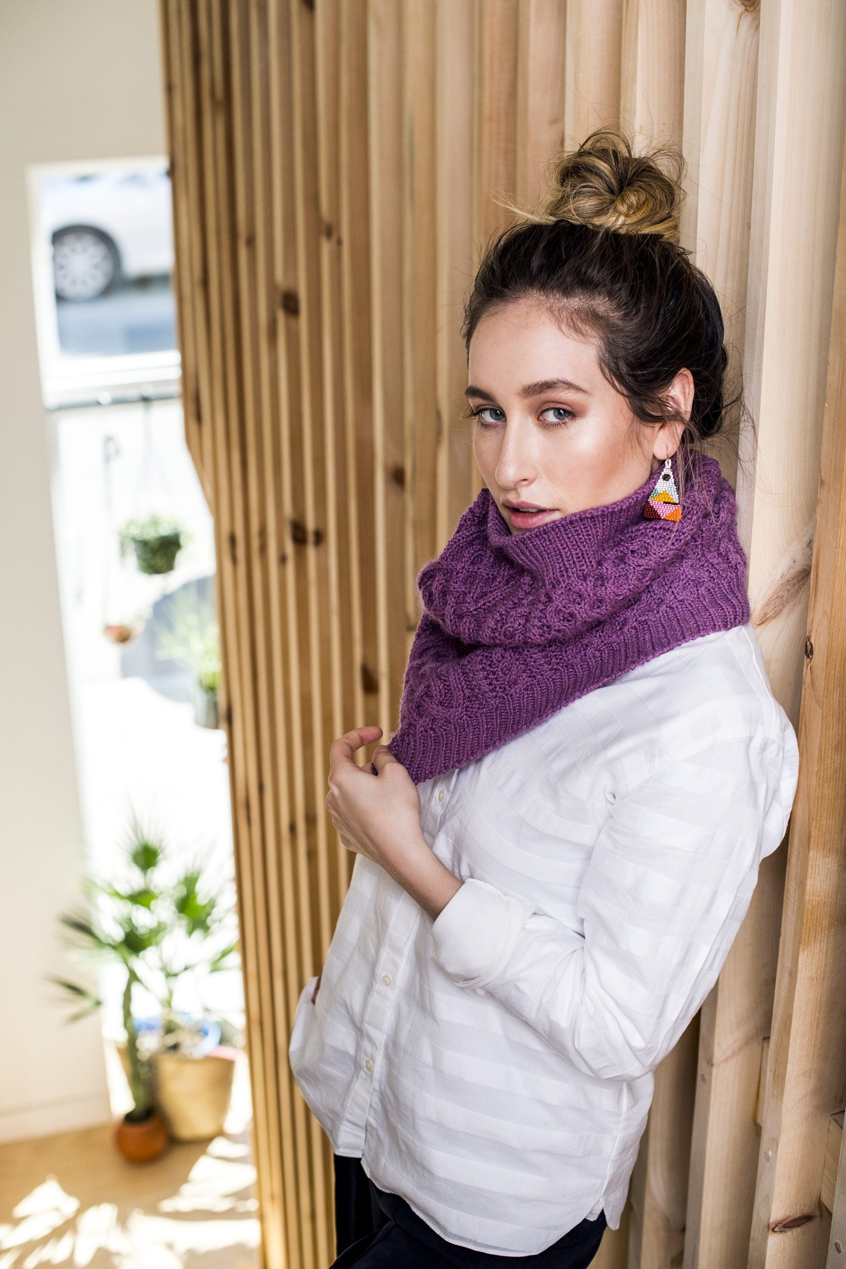 A Chinese American female wearing the heavily cabled Compass cowl in orchid heather pink.