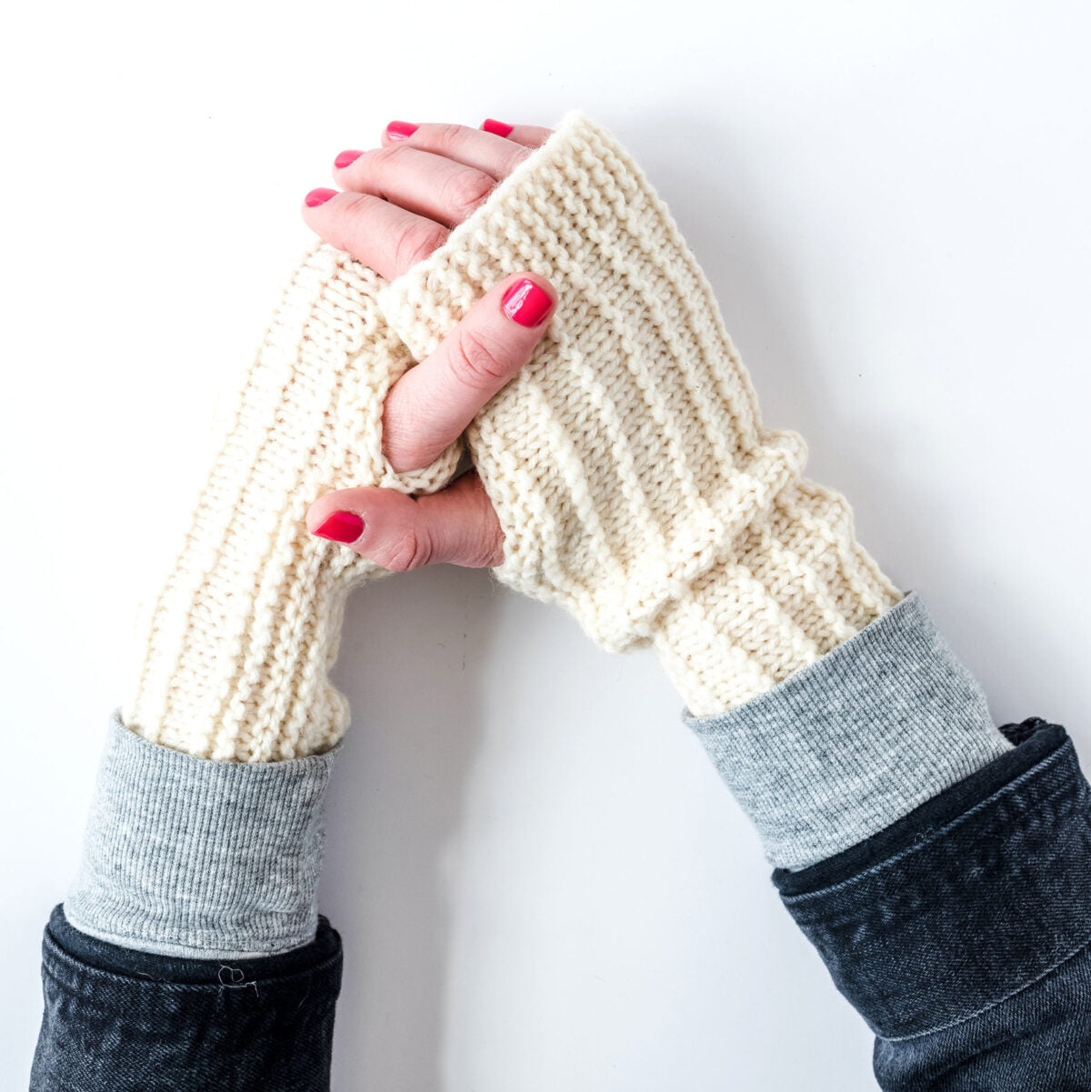 easy germantown yarn handwarmer. two hands clasped, wearing white wool handwarmers knit in kelbourne woolens' germantown yarn.
